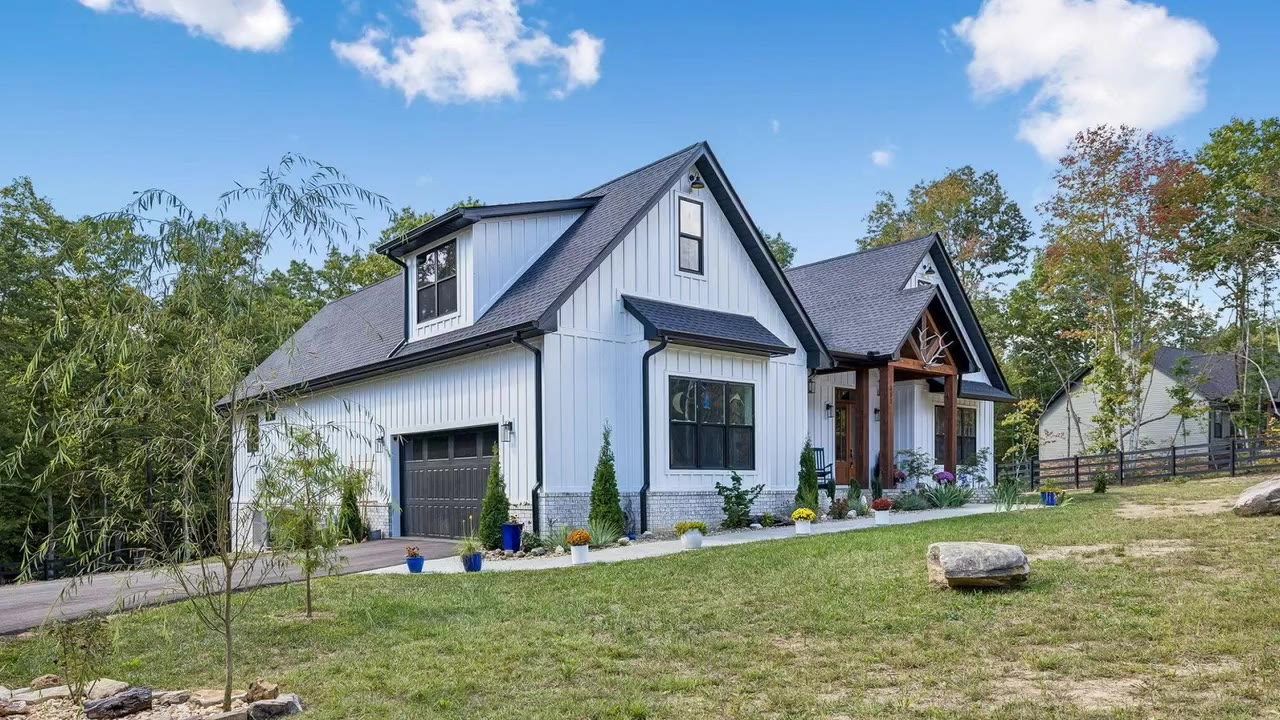A white farmhouse with a timber porch and a garden